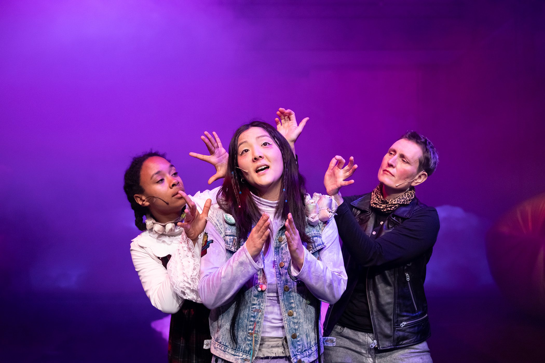 DreI Personen stehen zusammen. Die mittlere singt.